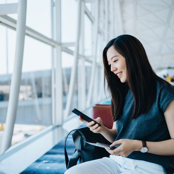 Woman holding passport and smartphone at the airport