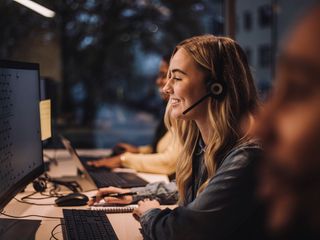 A smiling worker at her desk providing a great Customer Experience
