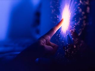 Hand touching digital screen with neon lines expanding