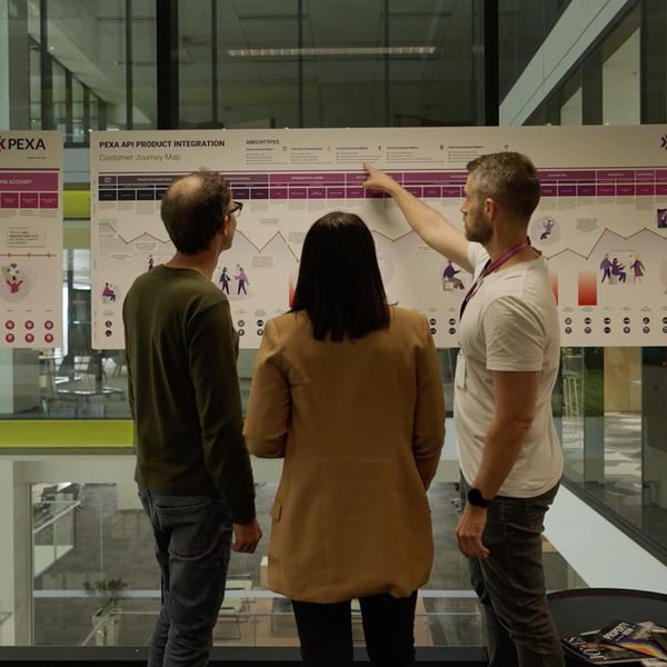 A team of two men and one woman looking at a customer journey board