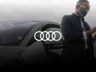 Black man charging his car while using his phone