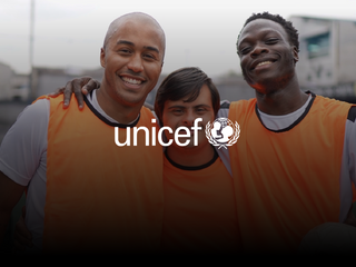 Two black man and a man with down syndrome using soccer uniform smiling at the camera