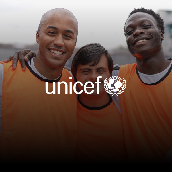 Two black man and a man with down syndrome using soccer uniform smiling at the camera