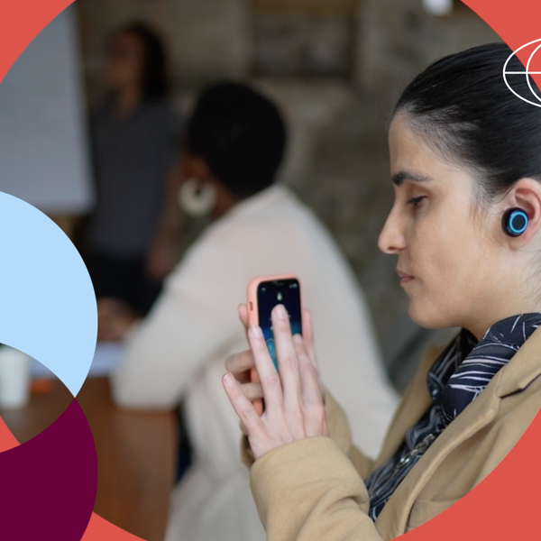 Empresária deficiente visual usando smartphone e fones de ouvido durante reunião de negócios