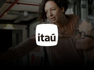 Ita&uacute; logo in white, and as background, an image of two women working together on a computer.