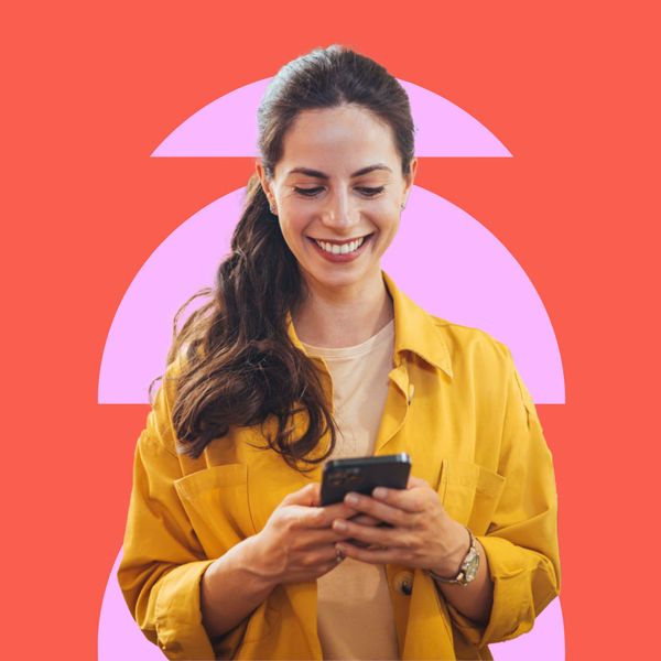 A woman in a yellow jacket holds a smartphone, standing against a orange background with pink geometric shapes.