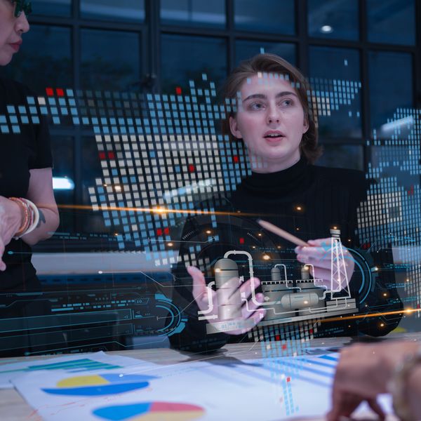Two women looking at a computer with computer graphics in front of her
