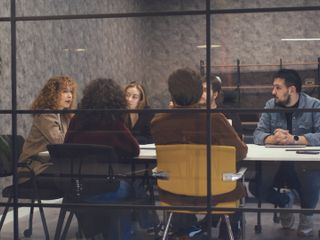 : A group of people seated around a conference table in a modern meeting room.