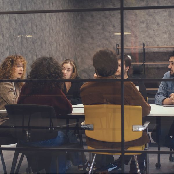 : A group of people seated around a conference table in a modern meeting room.