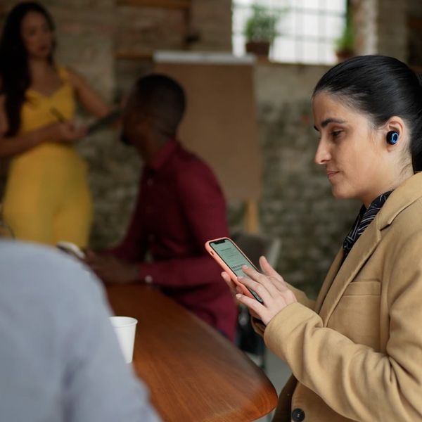Visually impaired businesswoman using smartphone and earphones during a business meeting