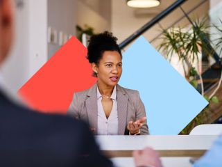 Businesswoman sitting at a table, leading a meeting with colleagues in a modern office