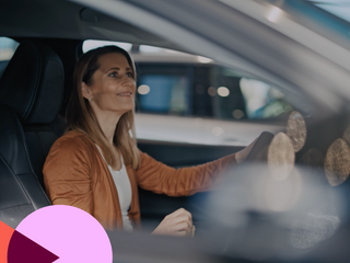 Mulher feliz sentada dentro de um carro novo em um showroom de carro