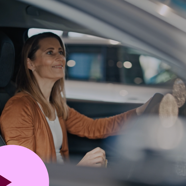 Mulher feliz sentada dentro de um carro novo em um showroom de carro