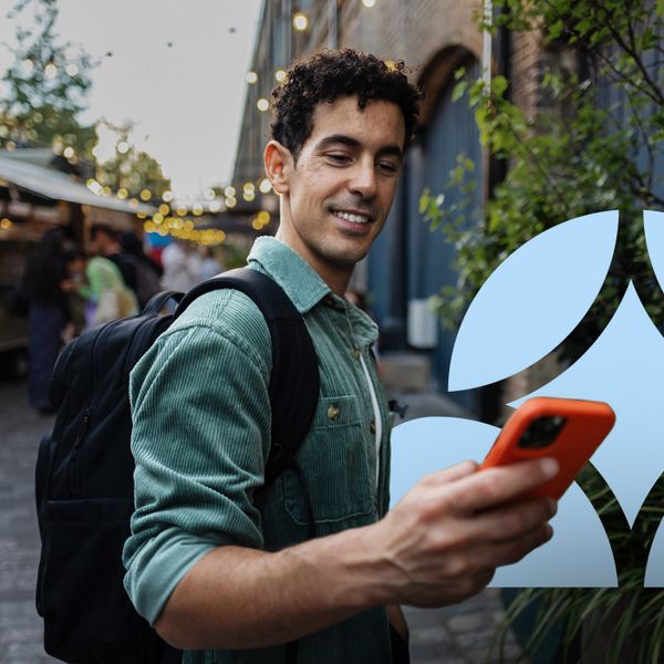 Smiling young latin man using a smartphone in a street market