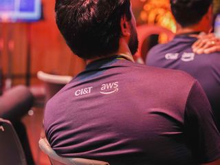 Back view of a person wearing a CI&T and AWS branded shirt at an event.