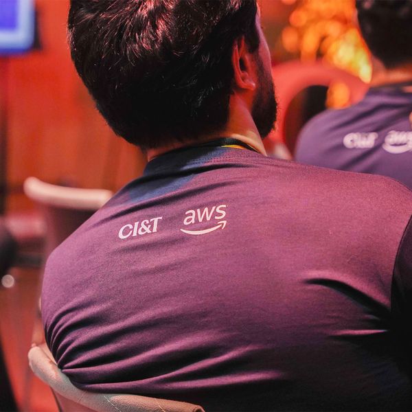 Back view of a person wearing a CI&T and AWS branded shirt at an event.
