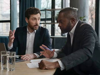 Agente de seguros de empres&aacute;rio caucasiano consultar cliente afro-americano do sexo masculino aconselhar ofertas financeiras mostrando apresenta&ccedil;&atilde;o no laptop. Dois homens de neg&oacute;cios diversos no escrit&oacute;rio discutem o projeto com computador