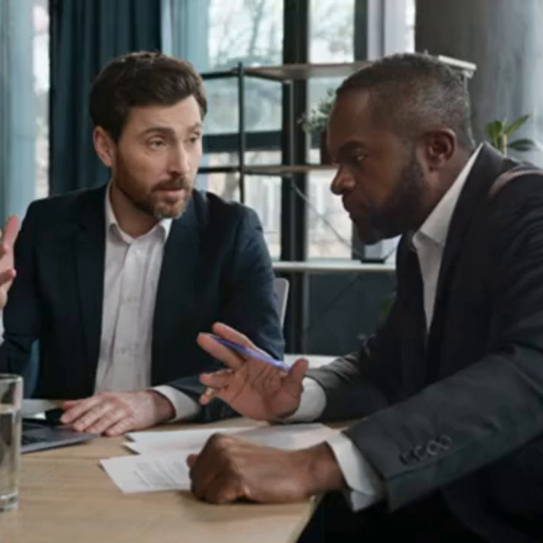 Agente de seguros de empresário caucasiano consultar cliente afro-americano do sexo masculino aconselhar ofertas financeiras mostrando apresentação no laptop. Dois homens de negócios diversos no escritório discutem o projeto com computador