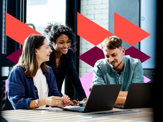 Three diverse colleagues&mdash;two women and one man&mdash;smile and collaborate around laptops in a bright, modern office setting, overlaid with vibrant geometric graphics.