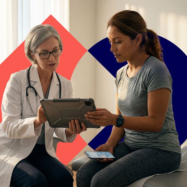 A female doctor and a patient reviewing health data on a tablet in a modern, sunlit medical office.