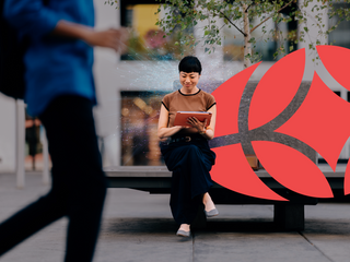 businesswoman sits on a bench in a city environment, using a digital tablet