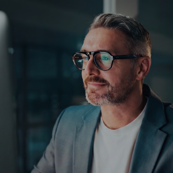 A man wearing glasses intently watching a computer screen.
